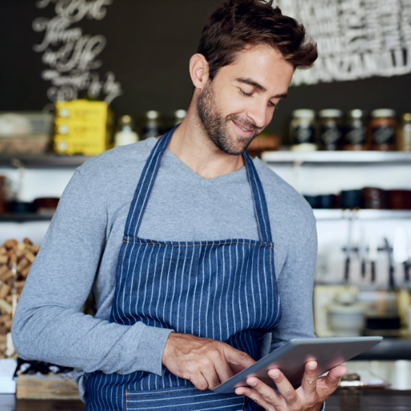 smiling man in apron using an ipad