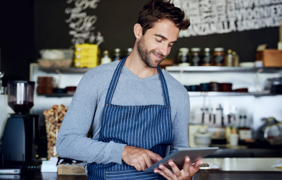 smiling man in apron using an ipad