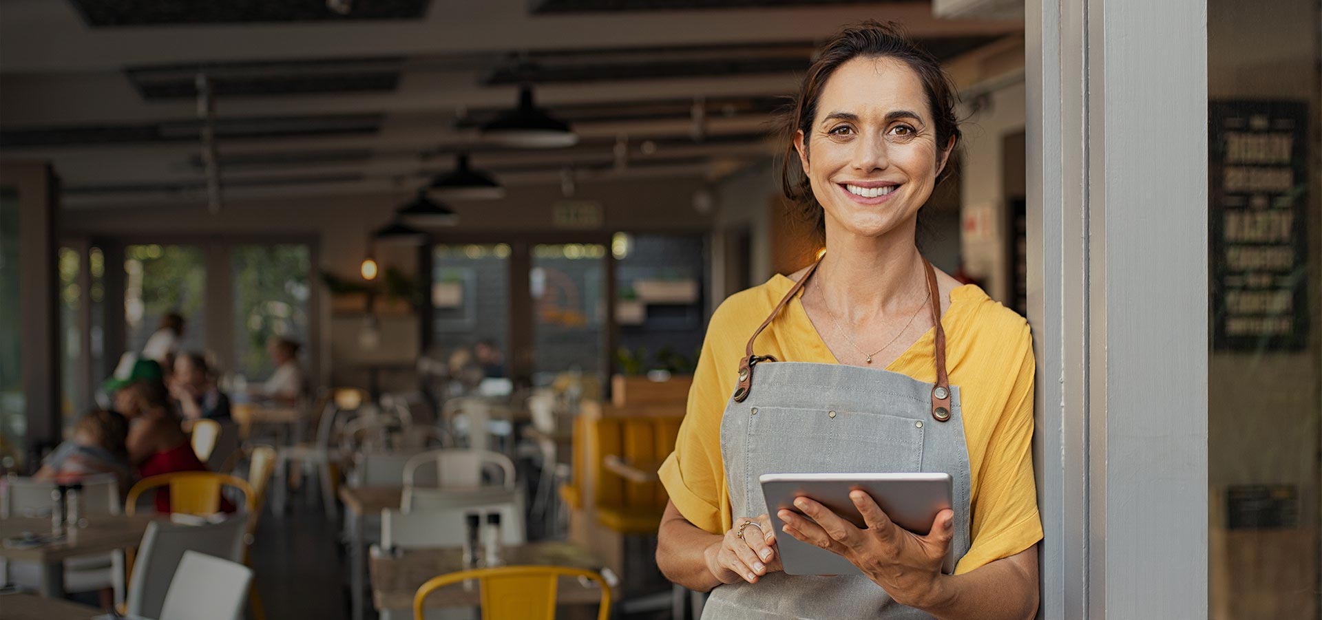 woman standing at entrance to a cafe, smiling